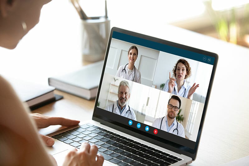 Close up of young female talk on video call consult with diverse doctors colleagues, woman patient have online consultation with GP or physicians, medical nurse in Webcam conference with coworkers